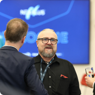 Nexalus team member talking to 2 people in front of tv in background