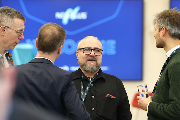 Nexalus team member talking to 2 people in front of tv in background